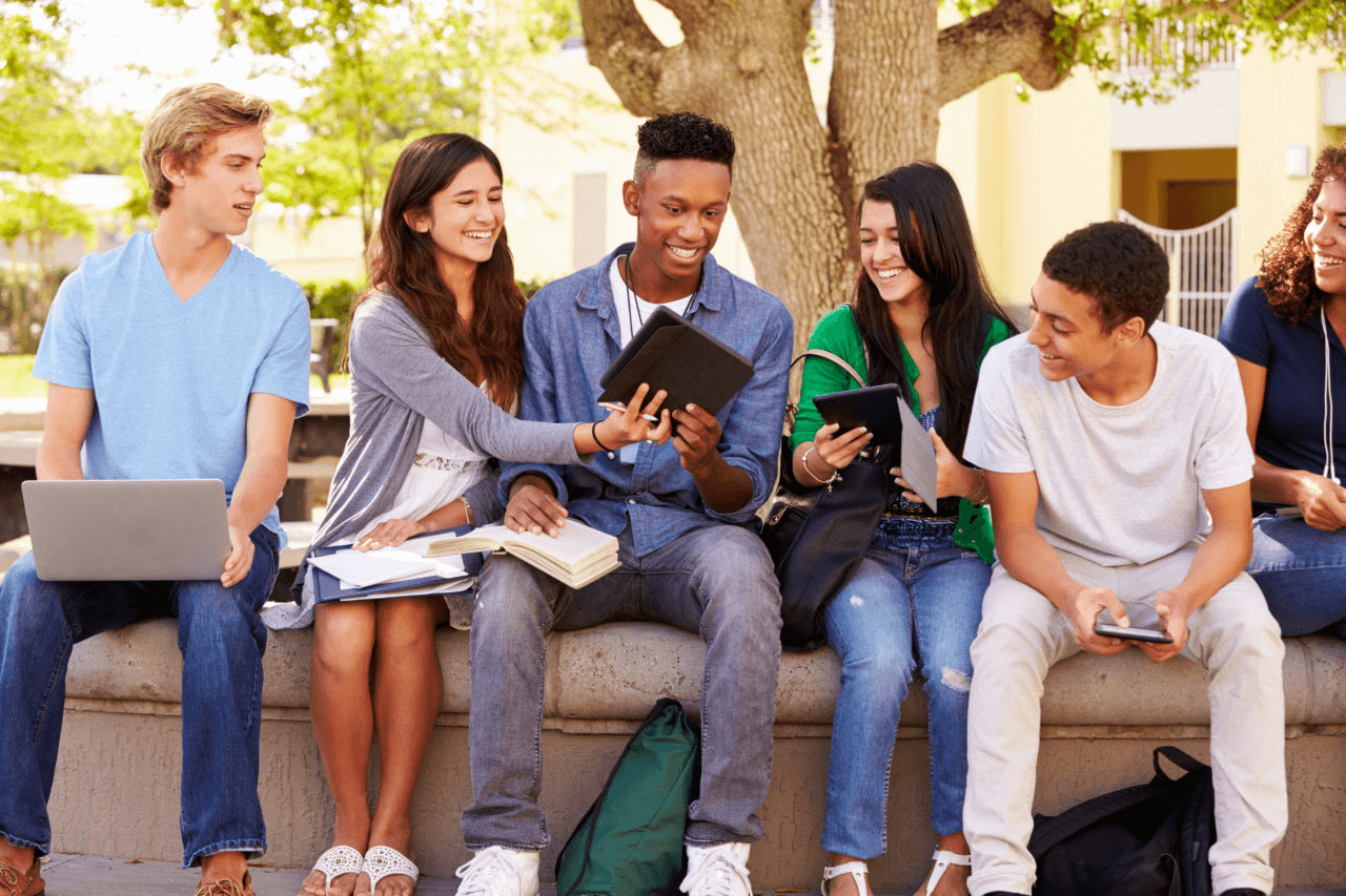 A group of young people sitting on top of a bench.