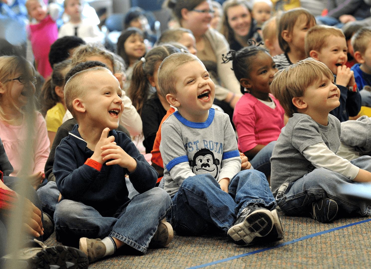 A group of children sitting on the floor laughing.